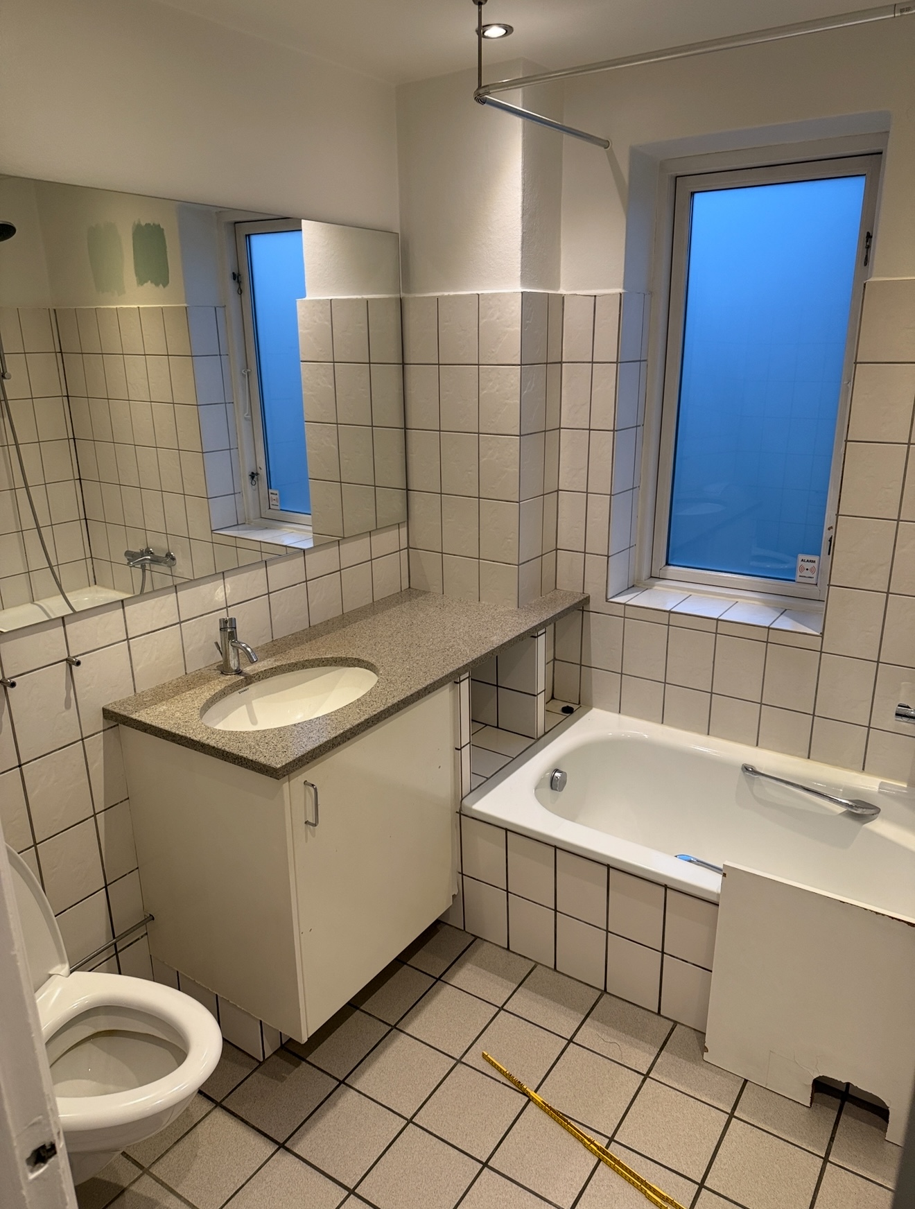 Ældre badeværelse med badekar og beige vægfliser før renovering