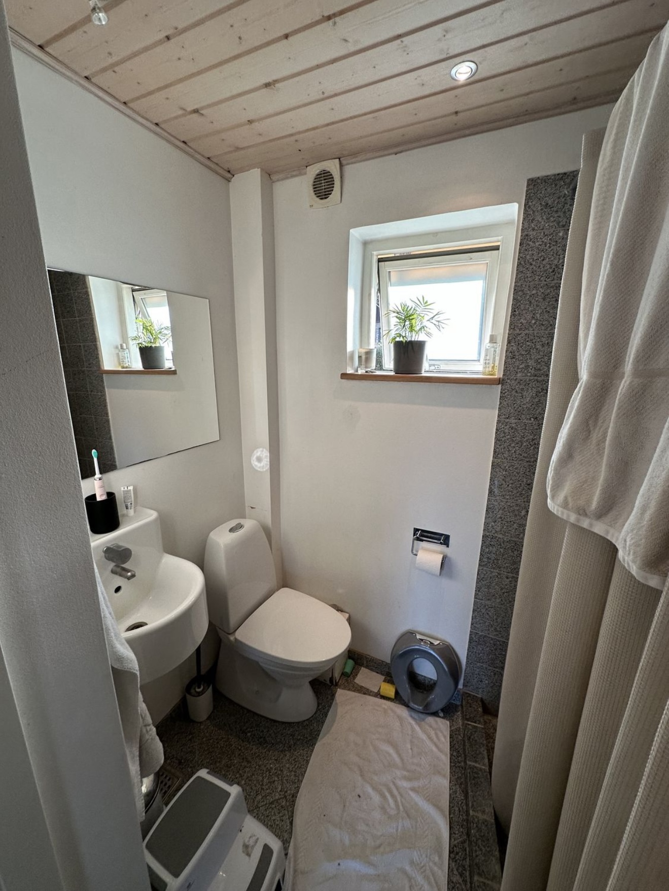 Færdigt badeværelse med spejl, toilet og lyse vægge
