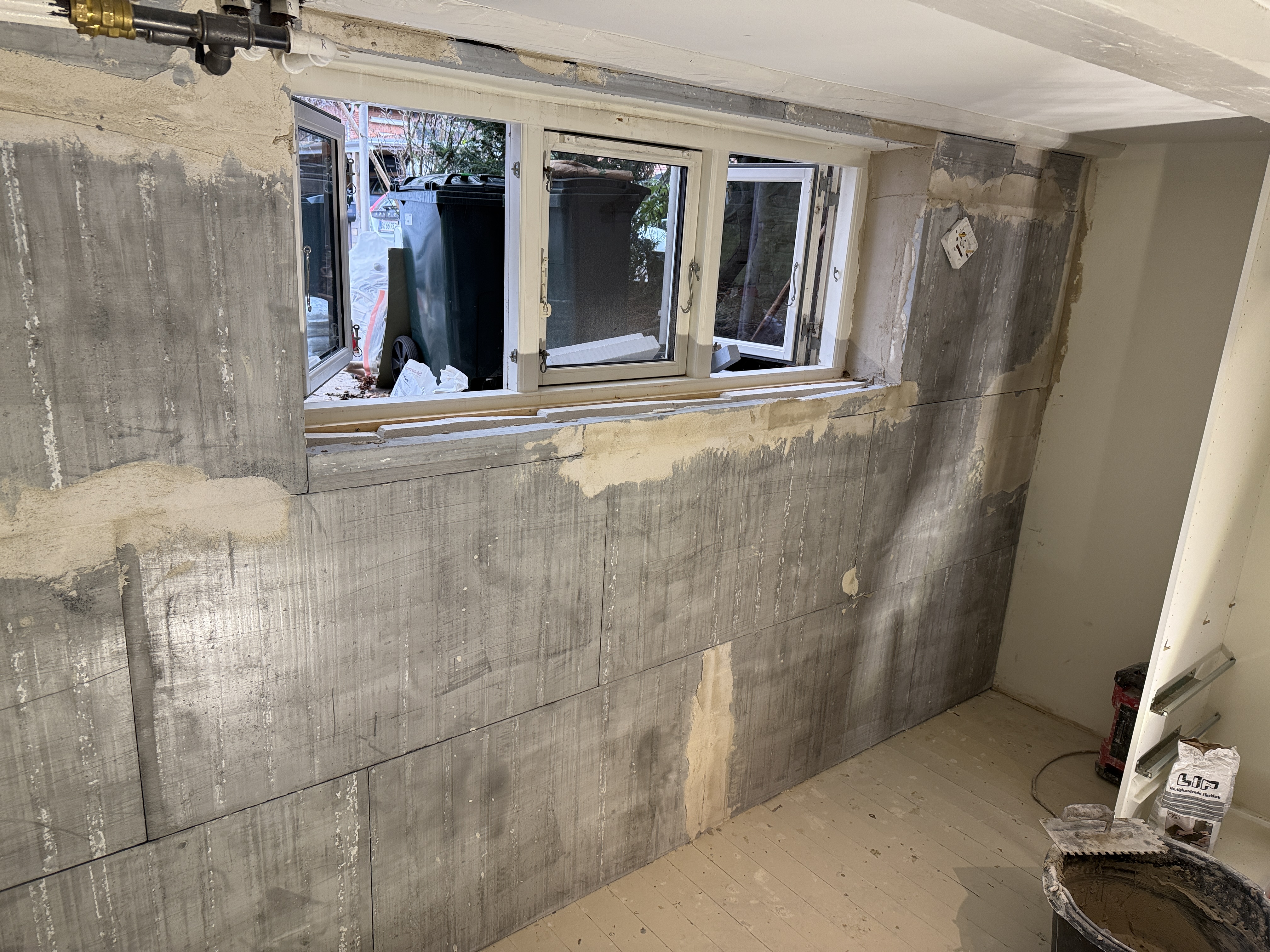 Bryggers under renovering – rå betonvæg omkring nyt kældervindue